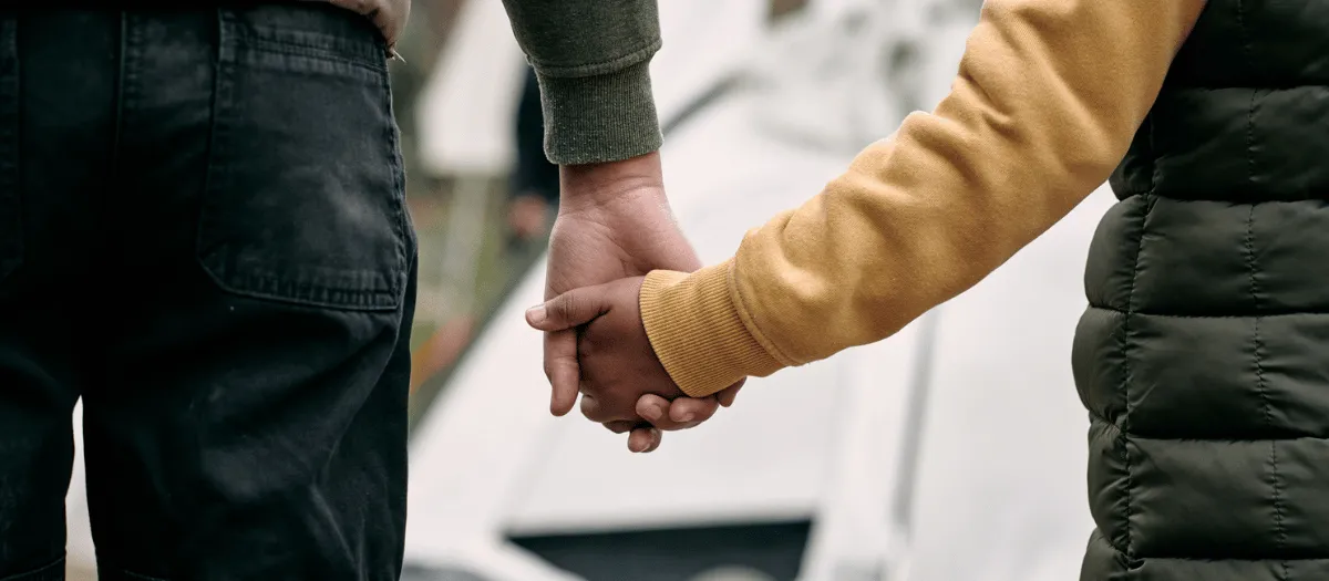 Child and adult hold hands outside of tent