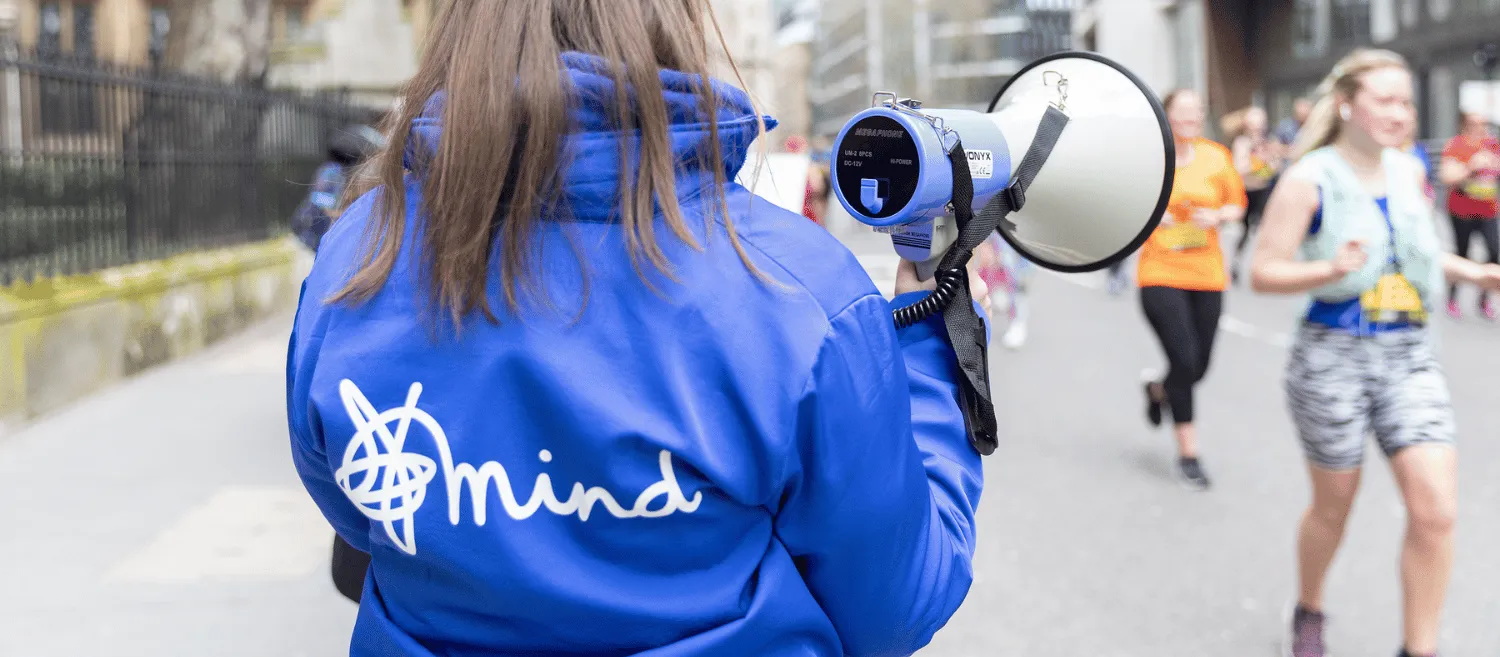 Lady holding megaphone wearing Mind jacket