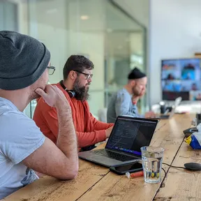 Kyle, Dan and Will working in the Bristol office with team members also on a zoom call on the screen